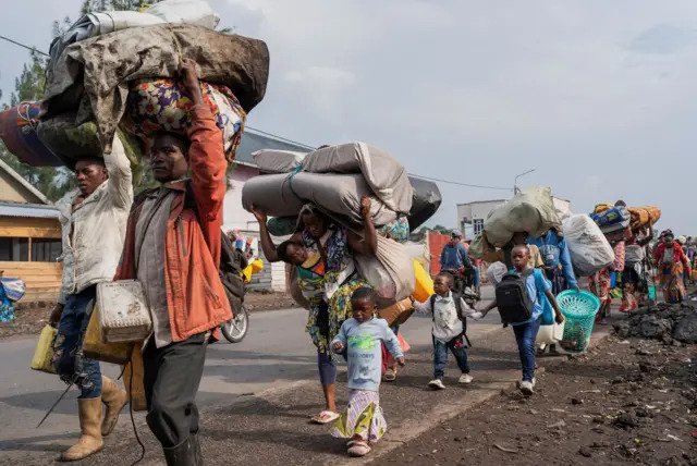 Familles en mouvement portant leurs effets personnels aux abords de Goma.